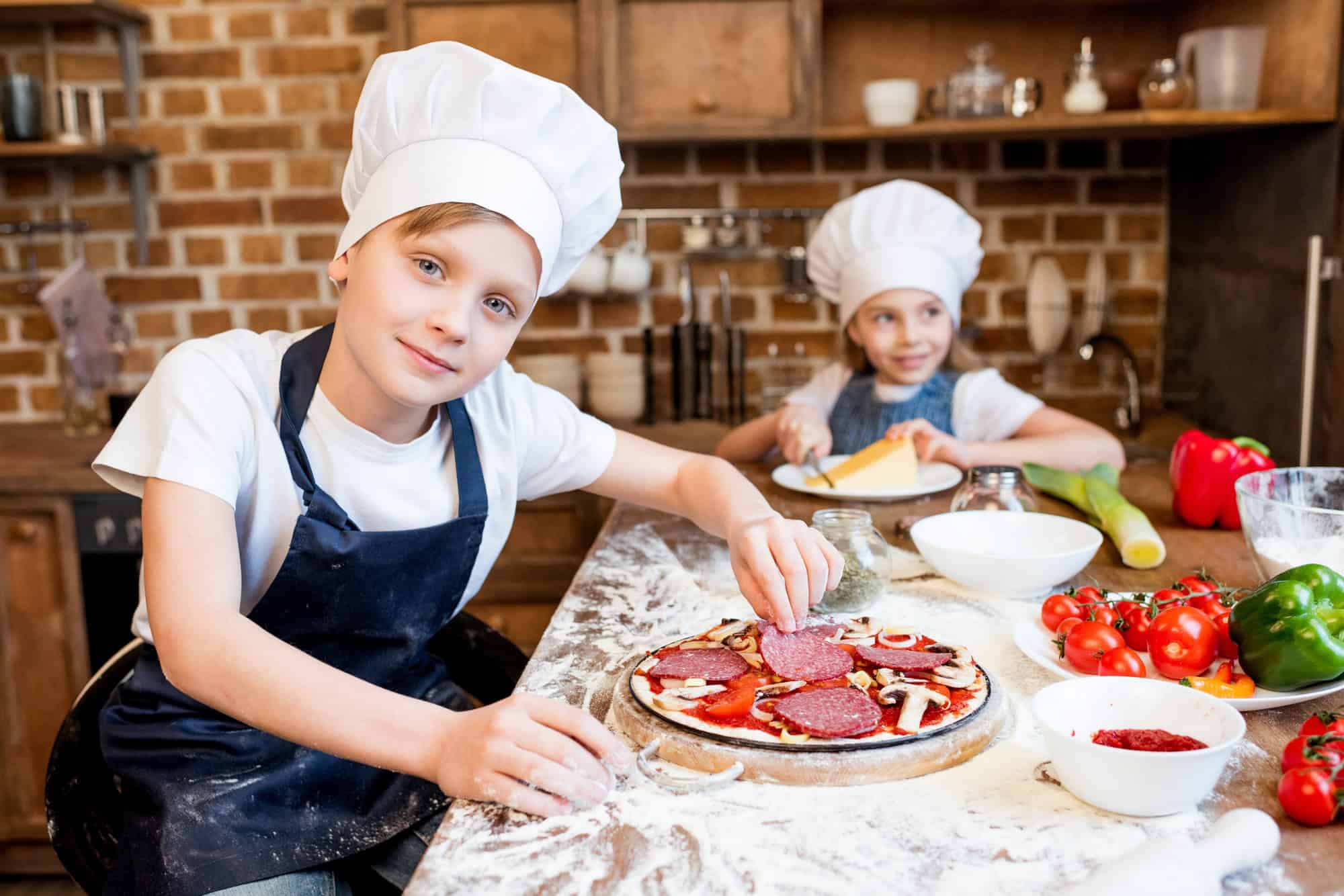 kids in chef hats making pizza together