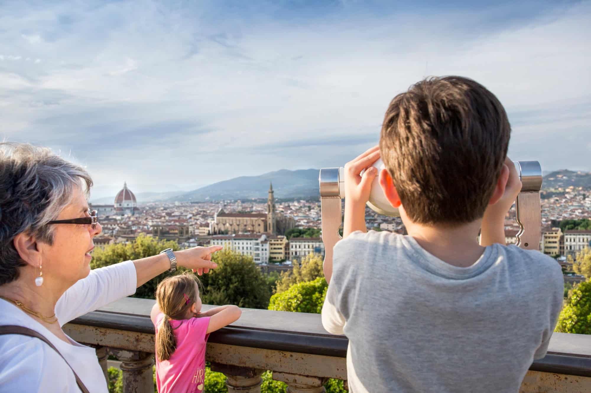 Senior woman and grandson looking at cityscape from coin operated binoculars, Florence, Italy