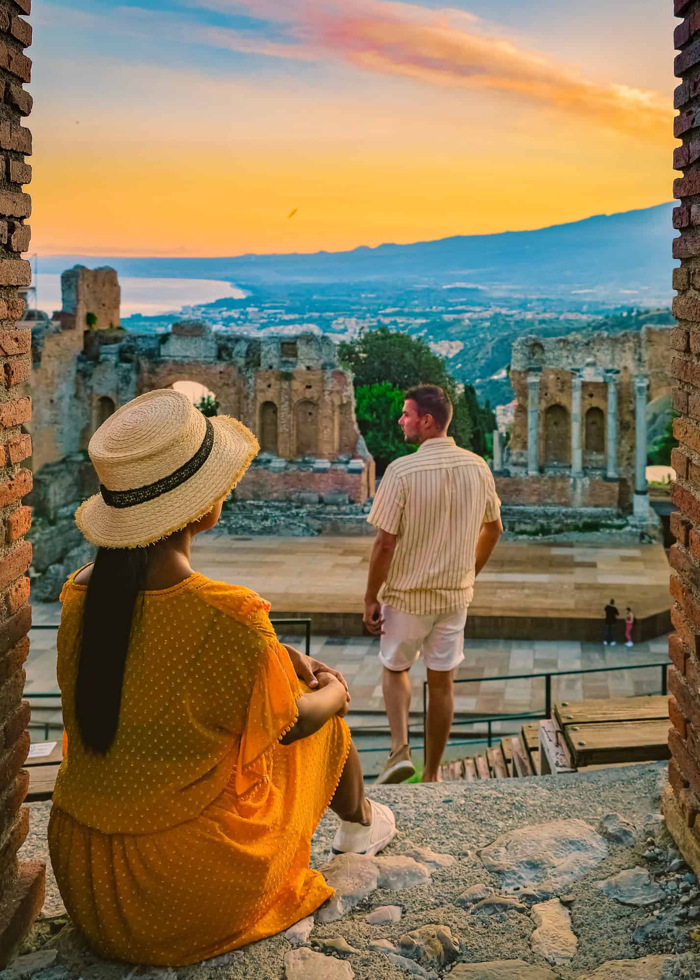 Taormina Sicily, couple watching sunset at the Ruins of the Ancient Greek Theater Taormina, Sicily